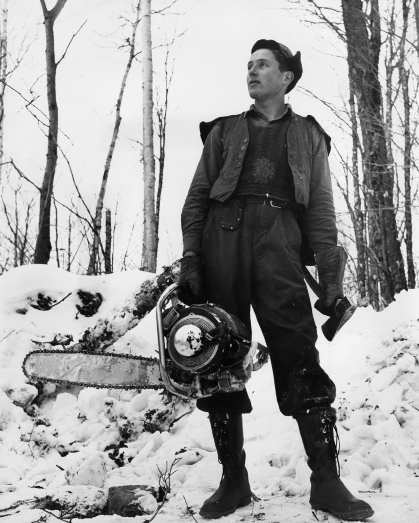 circa 1955: A lumberjack carrying a chainsaw and an axe. (Photo by Three Lions/Getty Images)