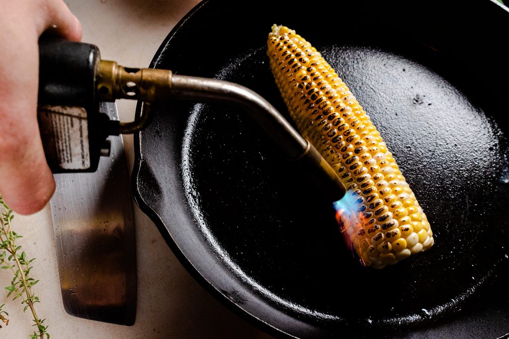 charring corn on the cob with blowtorch