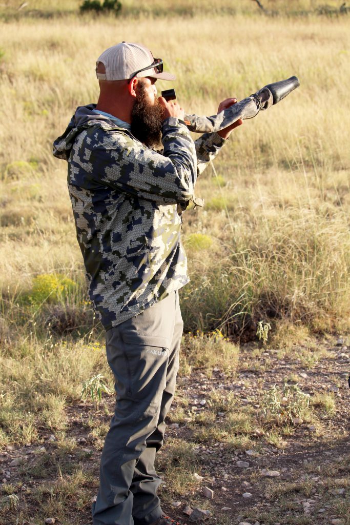 man bugles for elk in field