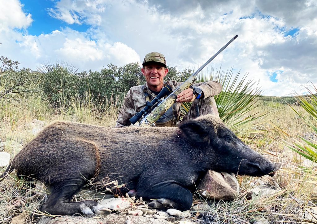 man with rifle and dead feral hog
