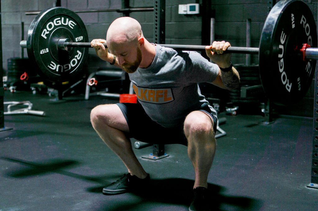 man doing squat with barbell proper squat technique