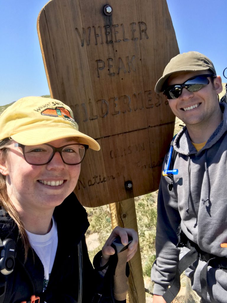 woman and man with wheeler peak wilderness sign